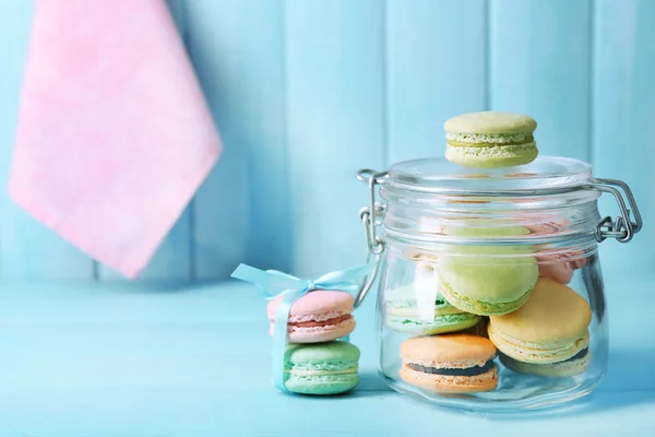 Gentle colorful macaroons in glass jar on color wooden table background — Φωτογραφία Αρχείου
