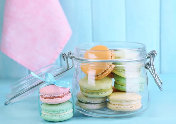 Gentle colorful macaroons in glass jar on color wooden table background — Stock Photo, Image