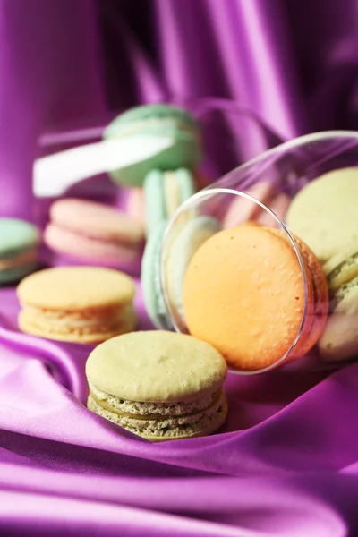 Gentle colorful macaroons in wine glass on color fabric background — Stock Photo, Image