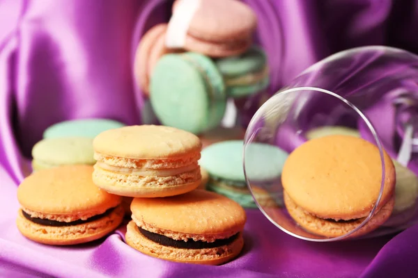 Gentle colorful macaroons in wine glass on color fabric background — Stock fotografie