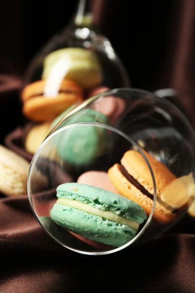 Macaroons coloridos suaves em vidro de vinho no fundo de tecido de cor — Fotografia de Stock