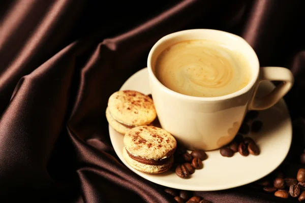 Gentle colorful macaroons and black coffee in mug on color fabric background — Zdjęcie stockowe