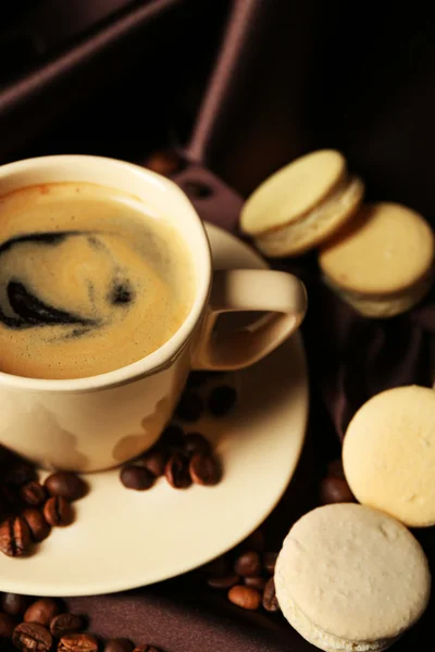 Gentle colorful macaroons and black coffee in mug on color fabric background — Stok fotoğraf