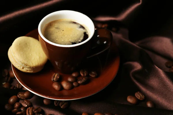 Gentle colorful macaroons and black coffee in mug on color fabric background — Zdjęcie stockowe