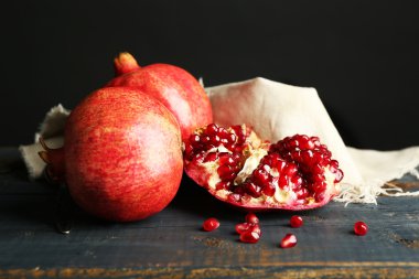 Koyu arka plan üzerinde ahşap masa üzerinde sulu olgun nar