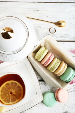 Ahşap arka plan üzerinde çay ile renkli macaroons