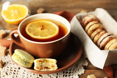 Ahşap arka plan üzerinde çay ile renkli macaroons