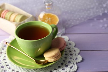 Ahşap arka plan üzerinde çay ile renkli macaroons