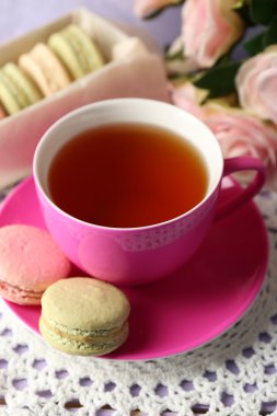 Ahşap arka plan üzerinde çay ile renkli macaroons