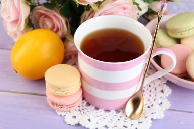Ahşap arka plan üzerinde çay ile renkli macaroons