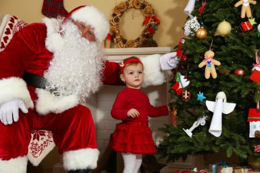 Noel Baba şömine ve Noel ağacı evde yakınındaki küçük sevimli kız için mevcut vererek