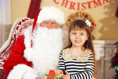 Noel Baba, evdeki Noel ağacının yanındaki küçük tatlı kıza hediye veriyor.