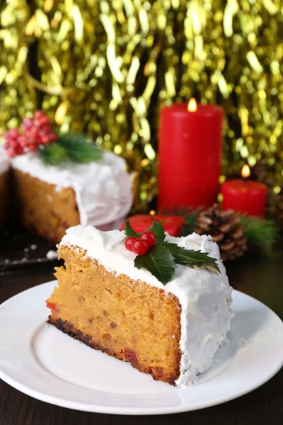 Rebanada de crema cubierta de pastel con decoración de Navidad en mesa de madera y fondo brillante — Foto de Stock