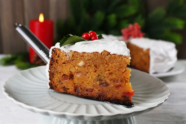 Kawałek ciasta pokryte krem z Bożego Narodzenia ozdoba na stół, na tle ściany drewniane — Zdjęcie stockowe