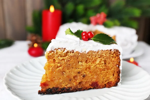 Fatia de bolo coberto de creme com decoração de Natal na mesa, no fundo da parede de madeira — Fotografia de Stock