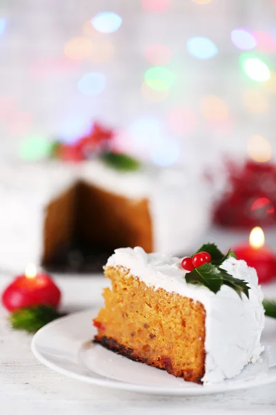 Кусок торта, покрытый сливками с рождественским декором на столе, на ярком фоне — стоковое фото