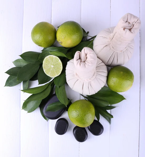 Spa composition with lime and compress balls on color wooden background — Stock Photo, Image
