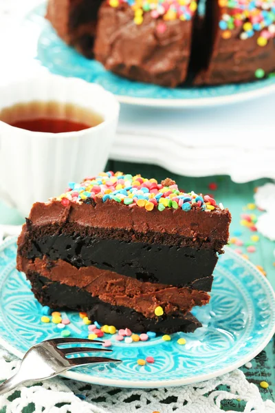 Шоколадный торт с красочным сладким порошком на столе крупным планом — стоковое фото