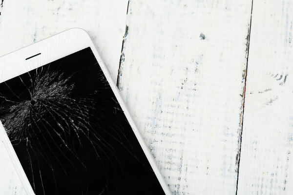 Сломанный iPhone на деревянном фоне
