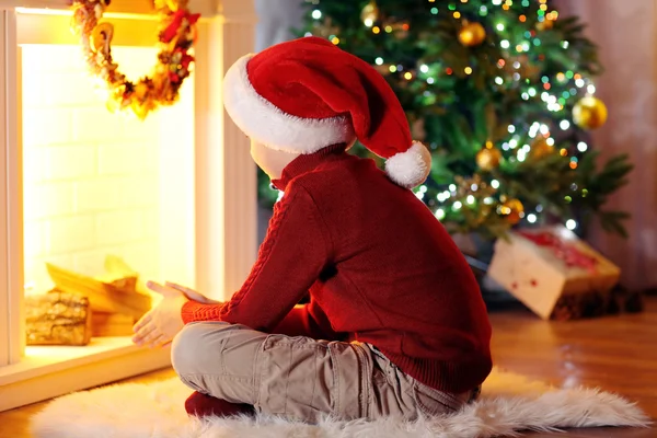 Little boy sitting near fireplace in room