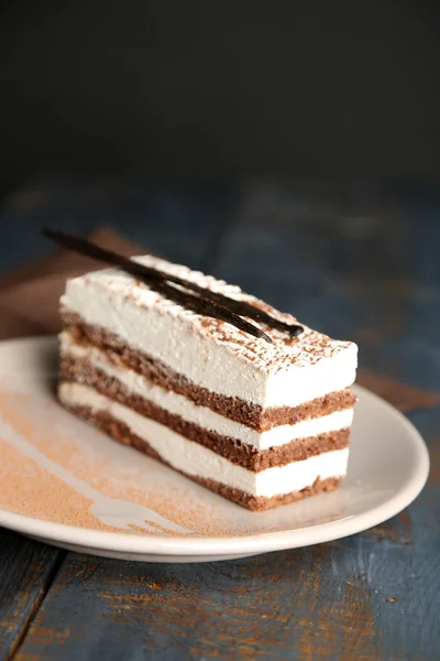 Lekkere tiramisu taart op plaat, op houten tafel, op zwarte achtergrond — Stockfoto