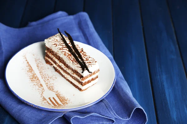 Tasty tiramisu cake on plate, on wooden table — Stock Photo, Image