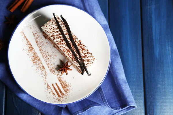 Tasty tiramisu cake on plate, on wooden table — Stock Photo, Image