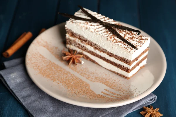 Tasty tiramisu cake on plate, on wooden table — Stock Photo, Image