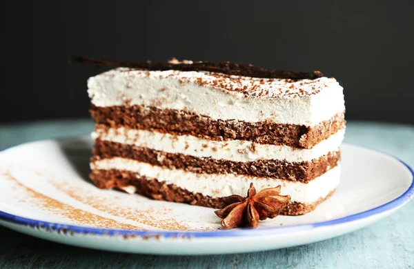 Bolo de tiramisu saboroso na placa, na mesa de madeira, no fundo preto — Fotografia de Stock