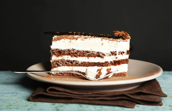 Gustosa torta tiramisù su piatto, su tavolo di legno, su fondo nero — Foto Stock