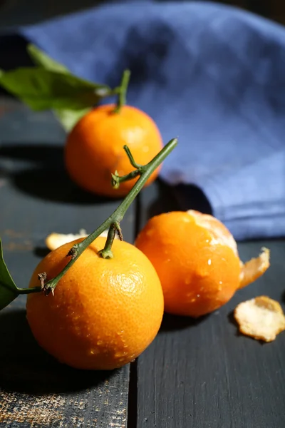 Šťavnaté zralé mandarinky s listy na dřevěném stole — Stock fotografie