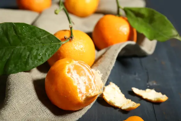 Juicy ripe tangerines with leaves on wooden table — Stock Photo, Image