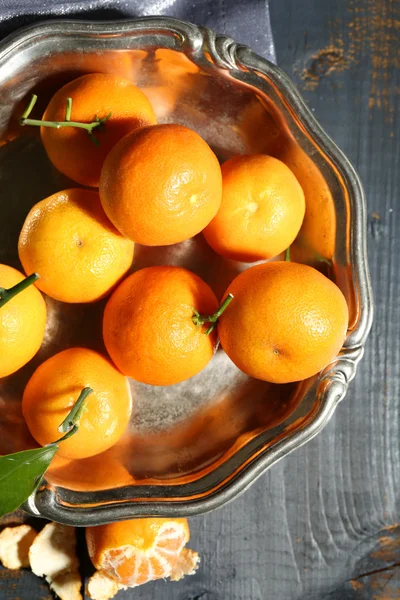 Sappige rijpe mandarijnen met bladeren op houten tafel — Stockfoto