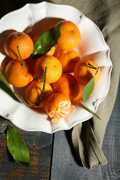 Soczyste dojrzałe mandarynki z liśćmi na drewnianym stole — Zdjęcie stockowe