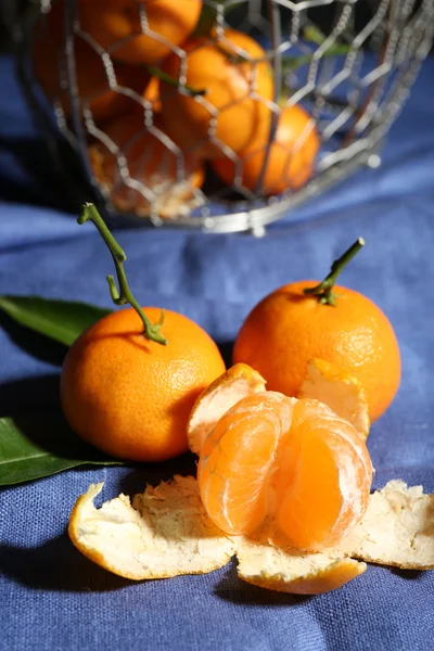 Mandarinas maduras jugosas con hojas en mantel —  Fotos de Stock