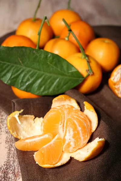 Juicy ripe tangerines with leaves on wooden table — Stock Photo, Image