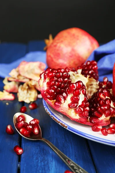 Juicy ripe pomegranates on wooden table, on dark background — Stock Photo, Image