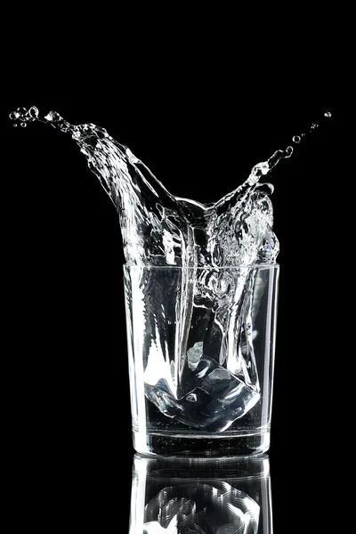 Water splash with ice in glass isolated on black — Stock Photo, Image