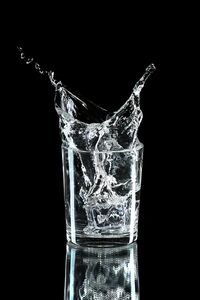 Water splash with ice in glass isolated on black — Stock Photo, Image