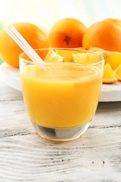 Verre de jus d'orange avec paille et tranches sur fond de table en bois — Photo