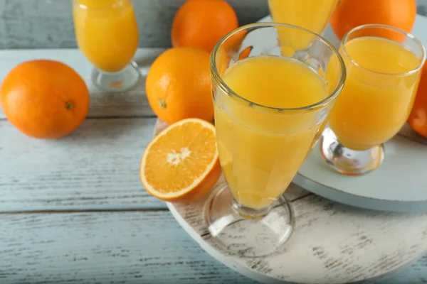 Bicchiere di succo d'arancia con fette su sfondo di legno a colori — Foto Stock