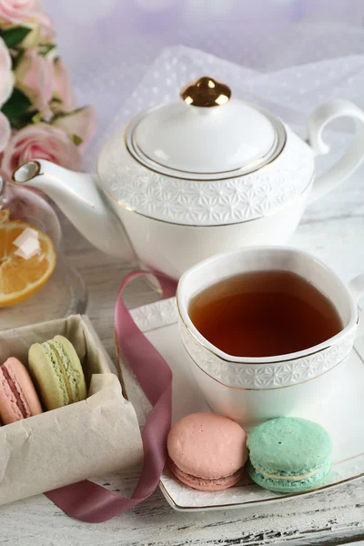 Composição com macaroons coloridos, bule de chá e até de chá sobre fundo de madeira cor — Fotografia de Stock