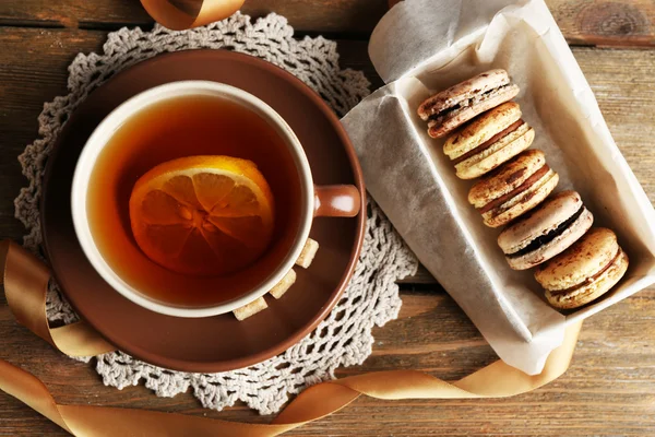 Macarons colorés avec tasse de thé sur fond en bois — Photo