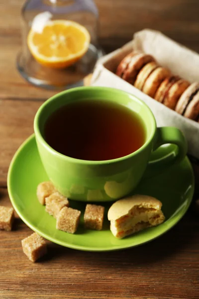 Färgglada macaroons med kopp te på trä bakgrund — Stockfoto