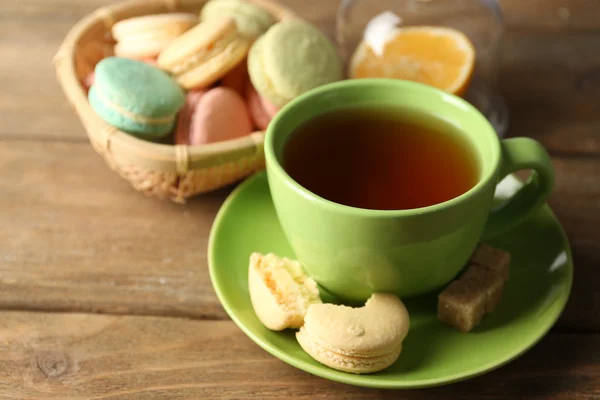 Macarons colorés avec tasse de thé sur fond en bois — Photo