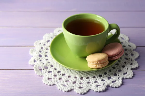 Šálek čaje s barevnými macarons na dřevěné pozadí — Stock fotografie