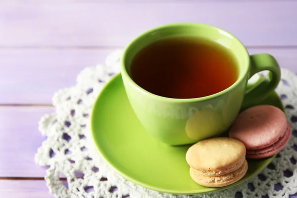 Kopp te med färgglada macarons på trä bakgrund — Stockfoto