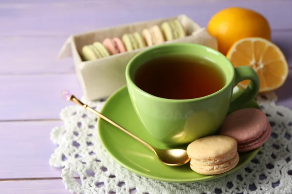 Färgglada macaroons med kopp te på trä bakgrund — Stockfoto