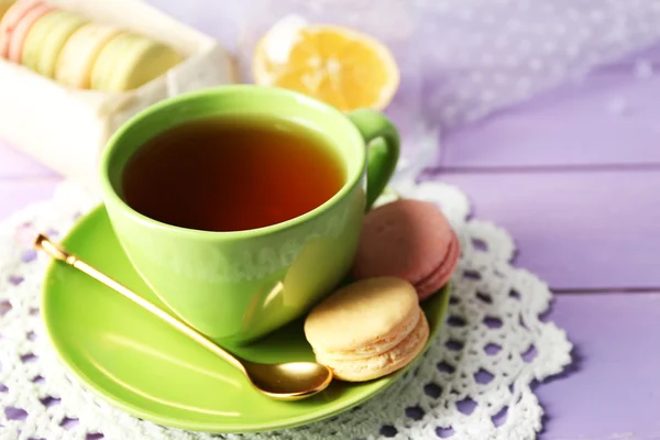 Macaroons coloridos com xícara de chá em fundo de madeira — Fotografia de Stock