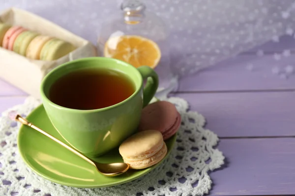 Macarons colorés avec tasse de thé sur fond en bois — Photo